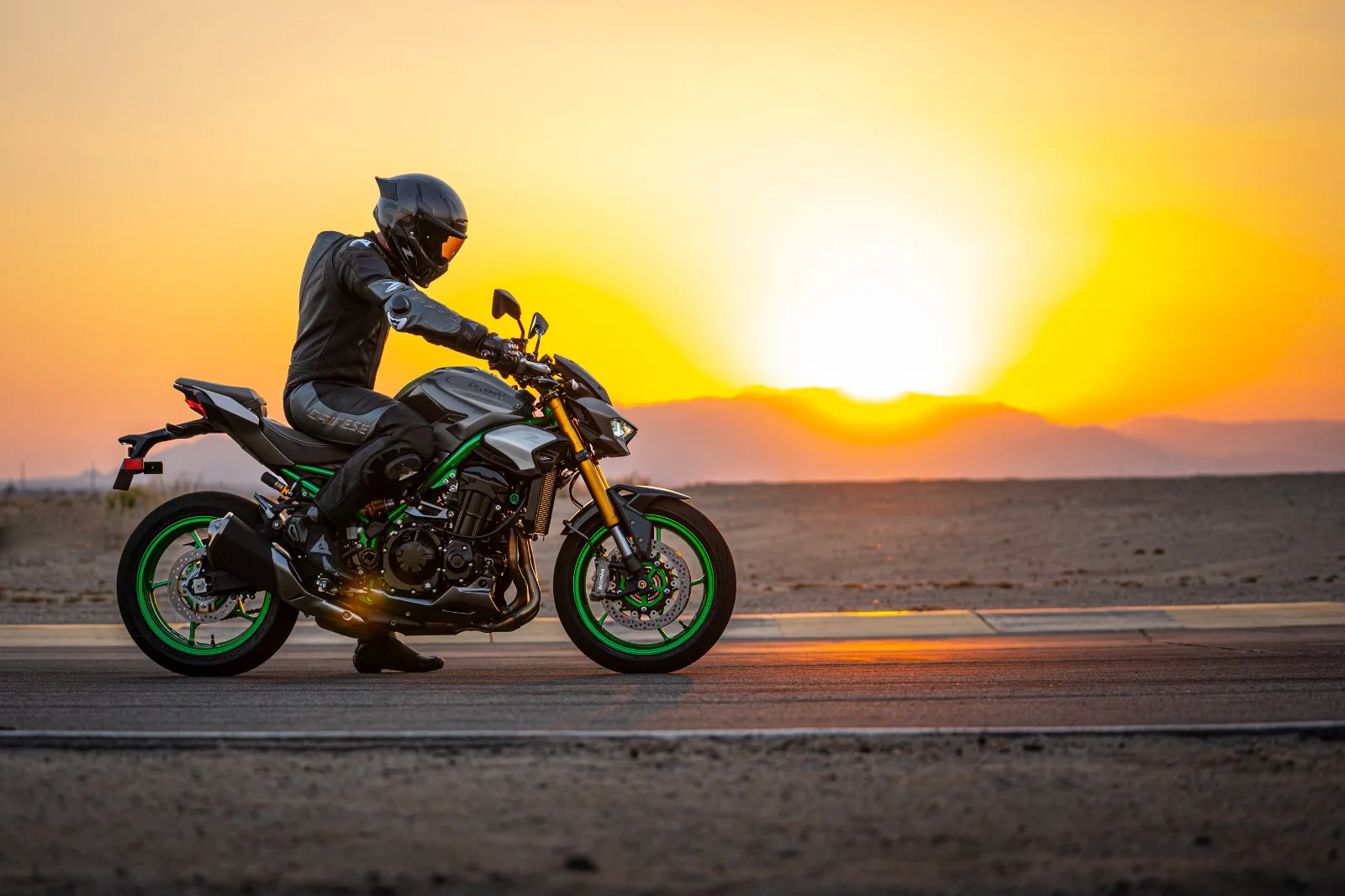 Vozač na Kawasaki naked motociklu pri zalasku sunca